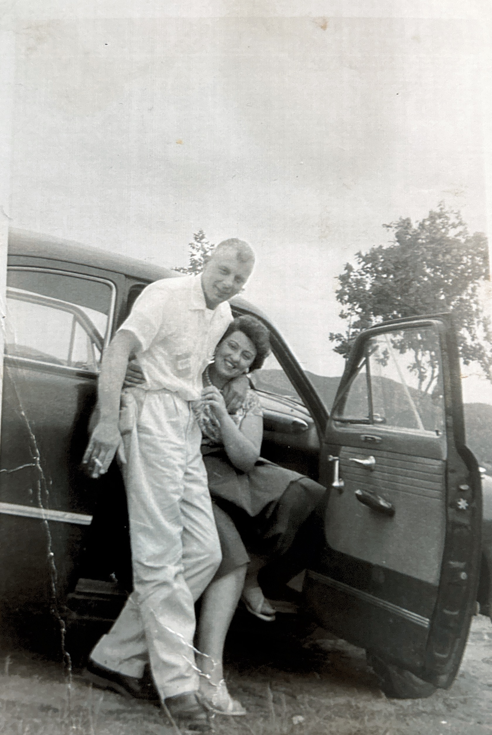 Dick leaning against a car with his arm around Mom, 1955